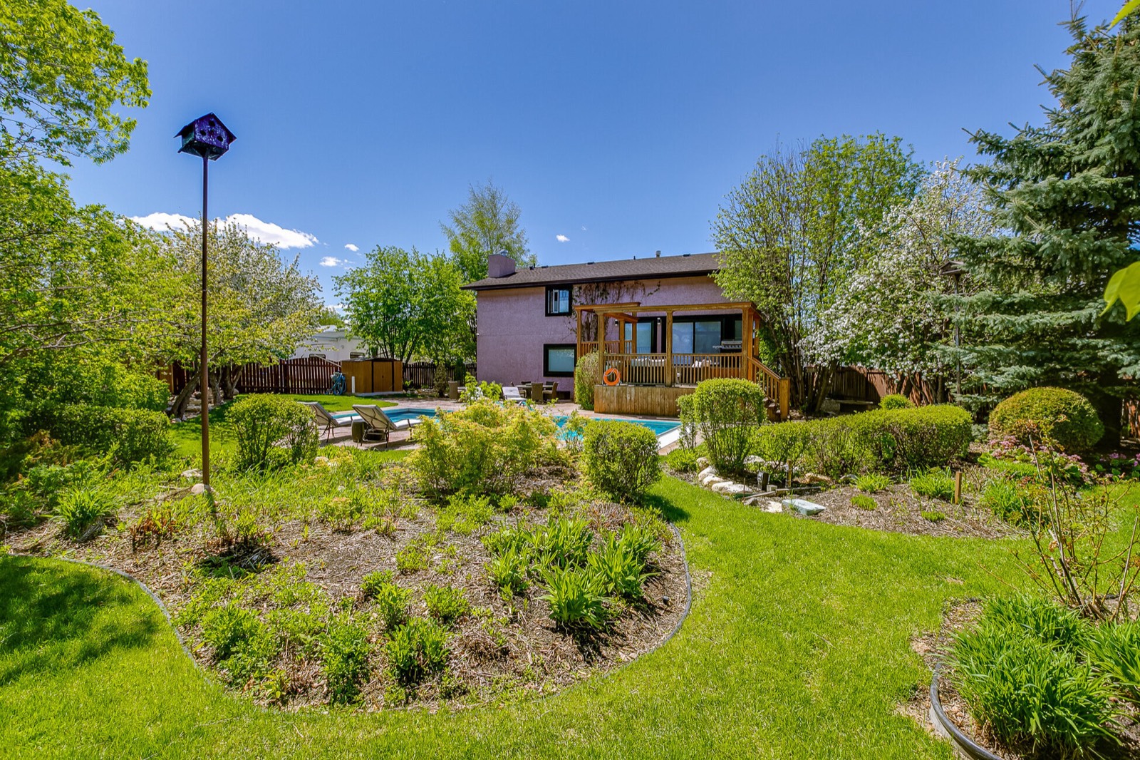 Mature landscaped backyard with a pool and a covered cedar deck at 402 Coben
