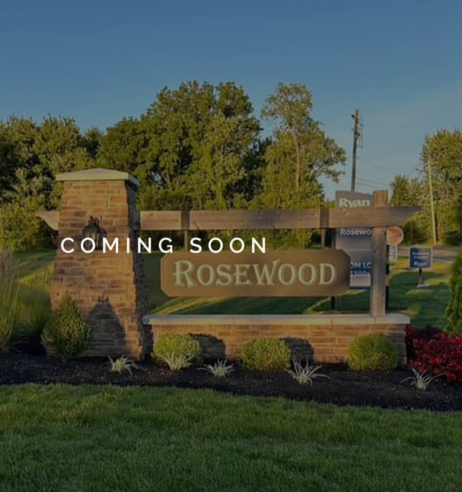Stone entry sign for Rosewood, marked Coming Soon, in early-evening light