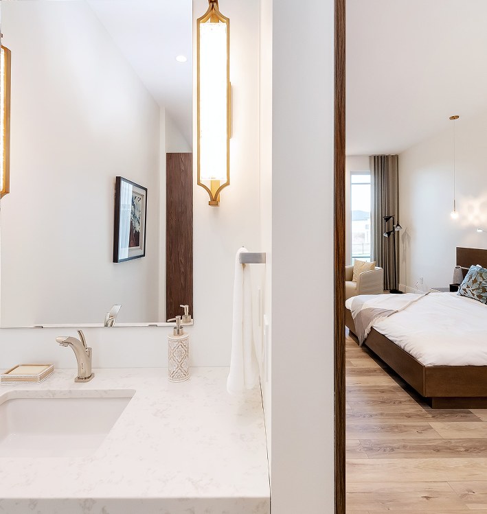 Primary bedroom seen from an ensuite with a gold wall sconce