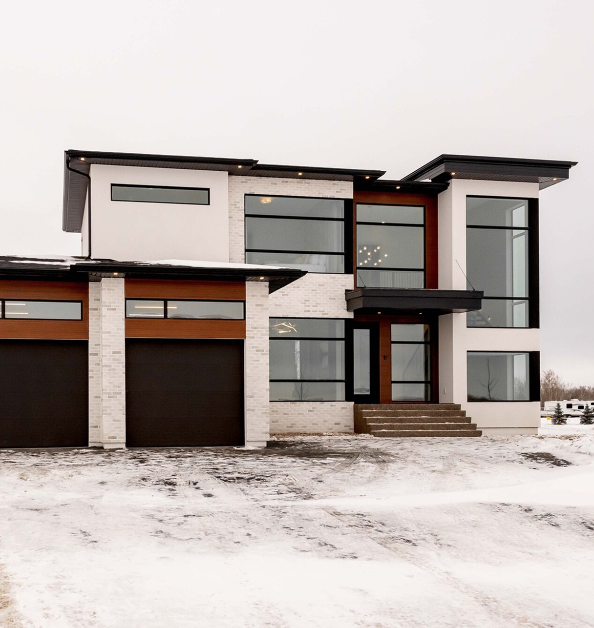Modern two-storey Decora home with black-framed windows and a double garage, in winter