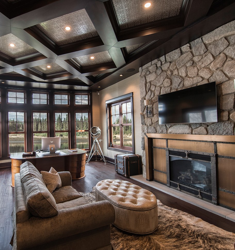 Living room with a coffered ceiling, stone fireplace and a wall of windows