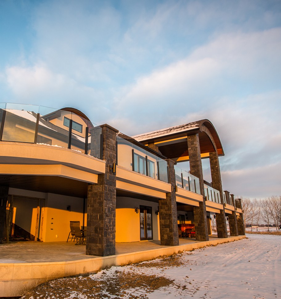 Rear of a renovated home at dusk, its decks and windows lit