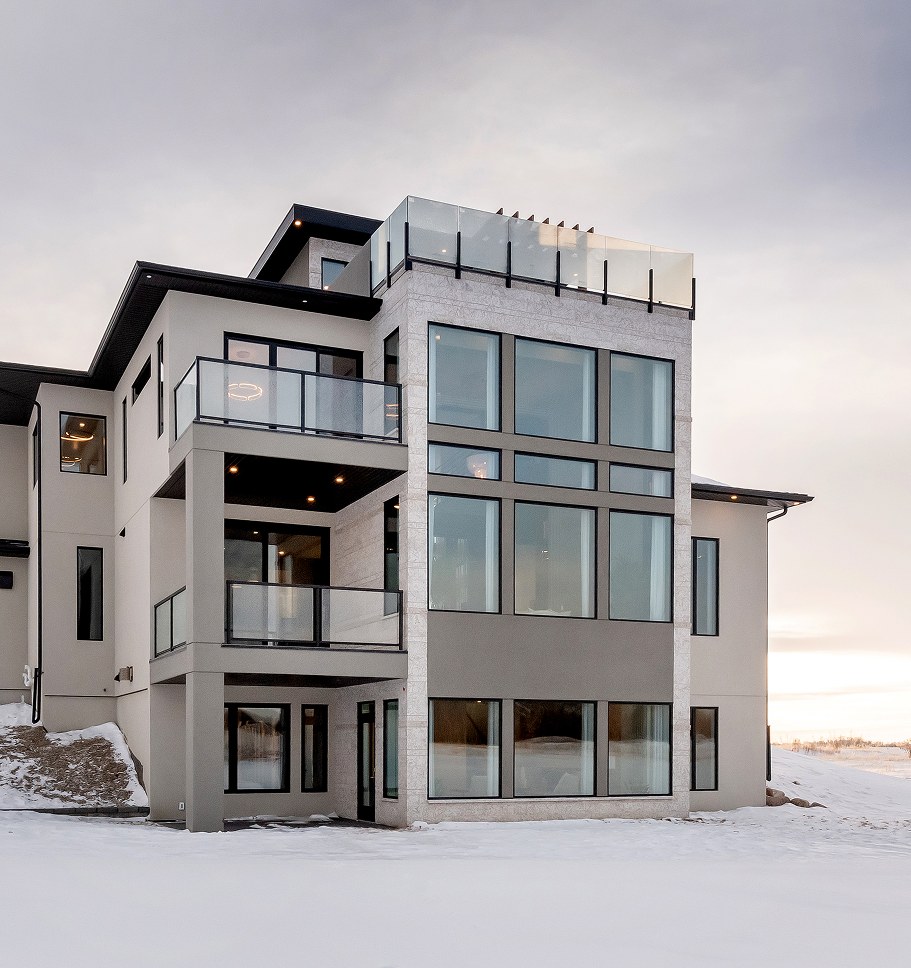 Three-storey modern home with glass railings and a rooftop deck, in winter