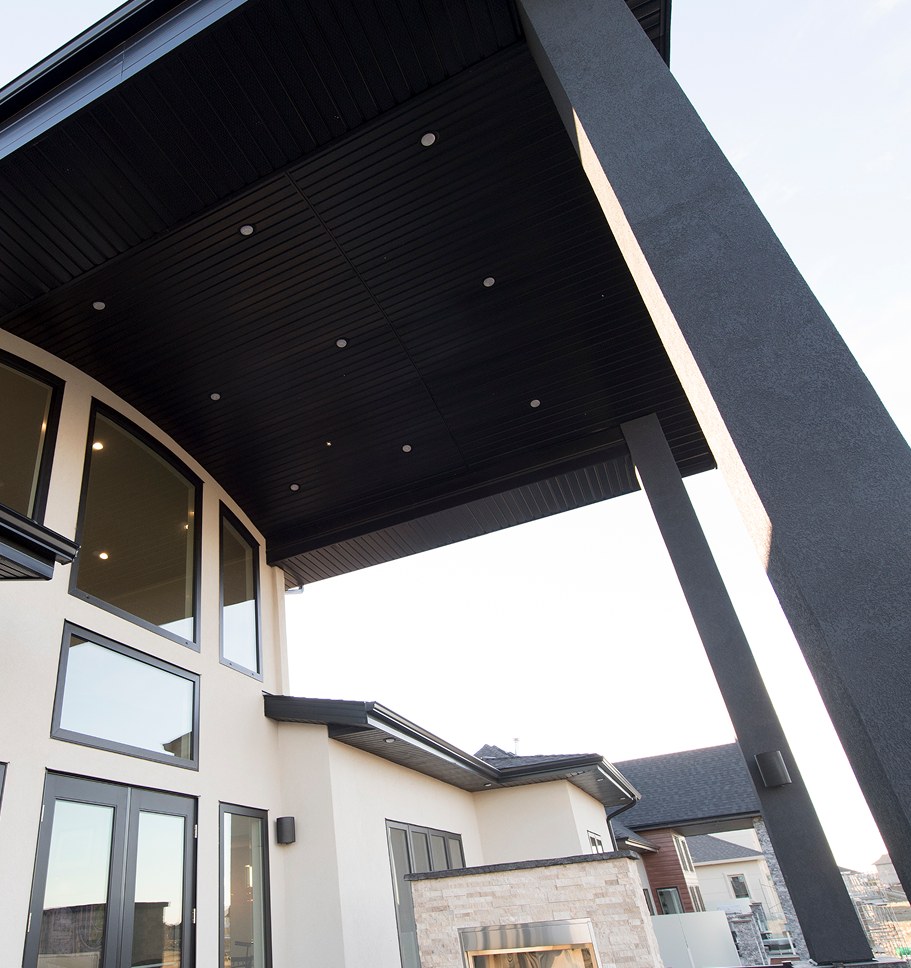 Looking up at a modern home’s cantilevered black roof against the sky