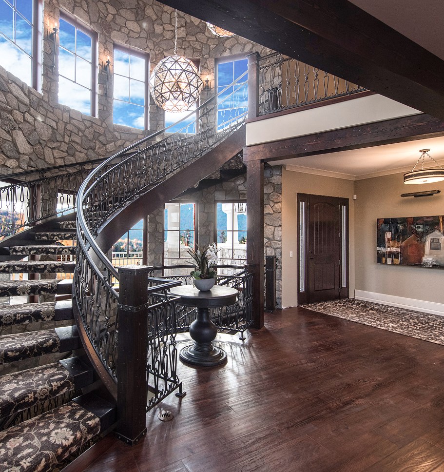 Curved staircase with an iron railing under a crystal chandelier