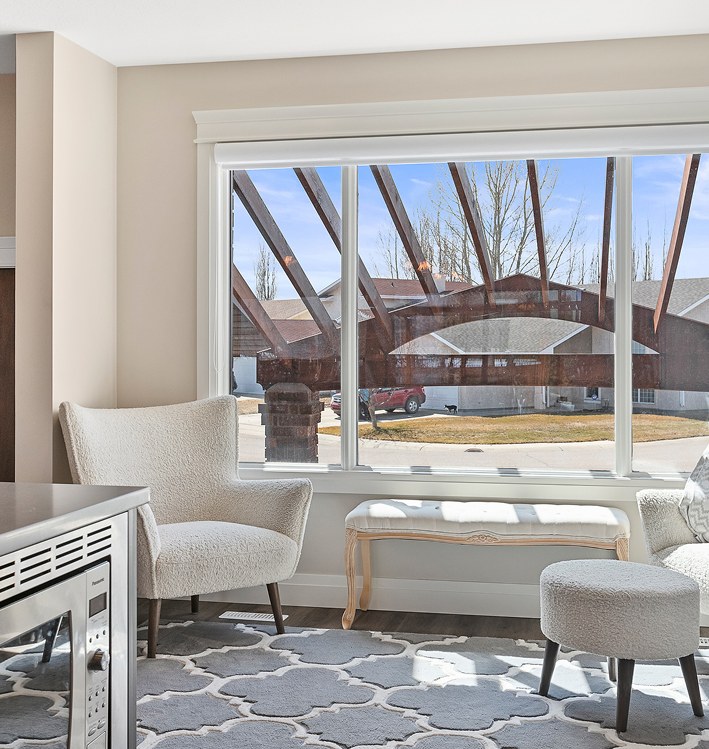 Sitting nook with white chairs and an upholstered bench beside a large window