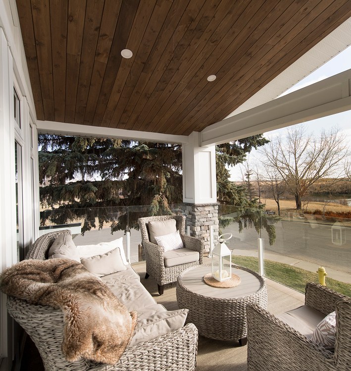 Covered patio with a wood ceiling and lounge seating overlooking a lawn