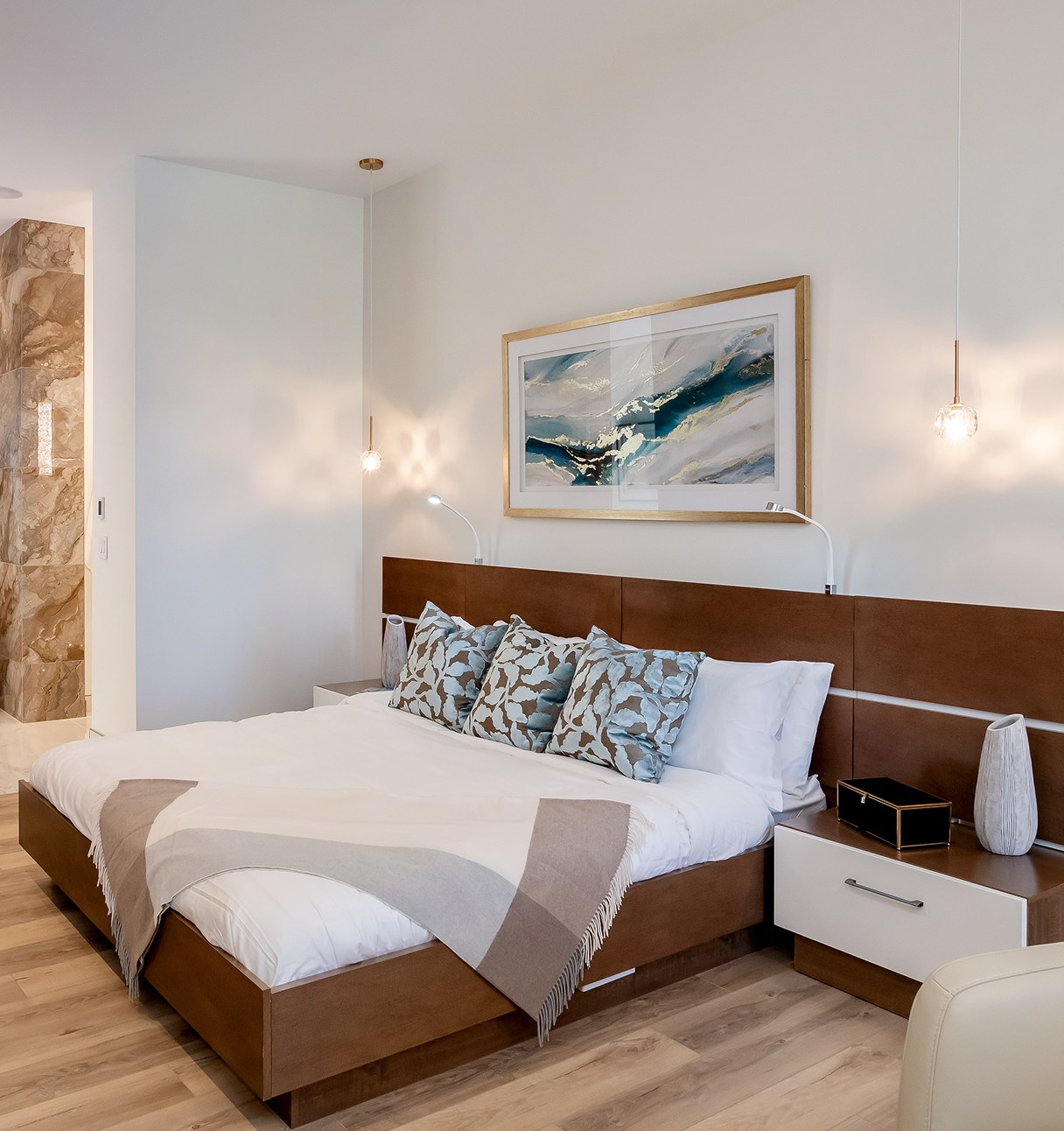 Primary bedroom with a walnut headboard wall, layered bedding and soft natural light