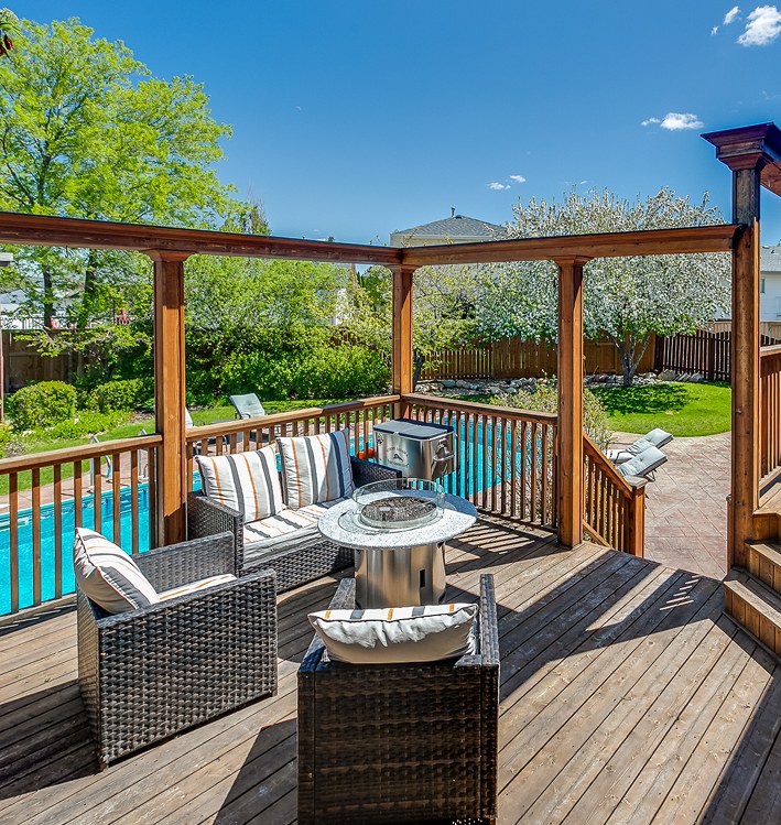 Covered cedar deck with outdoor seating beside a backyard pool
