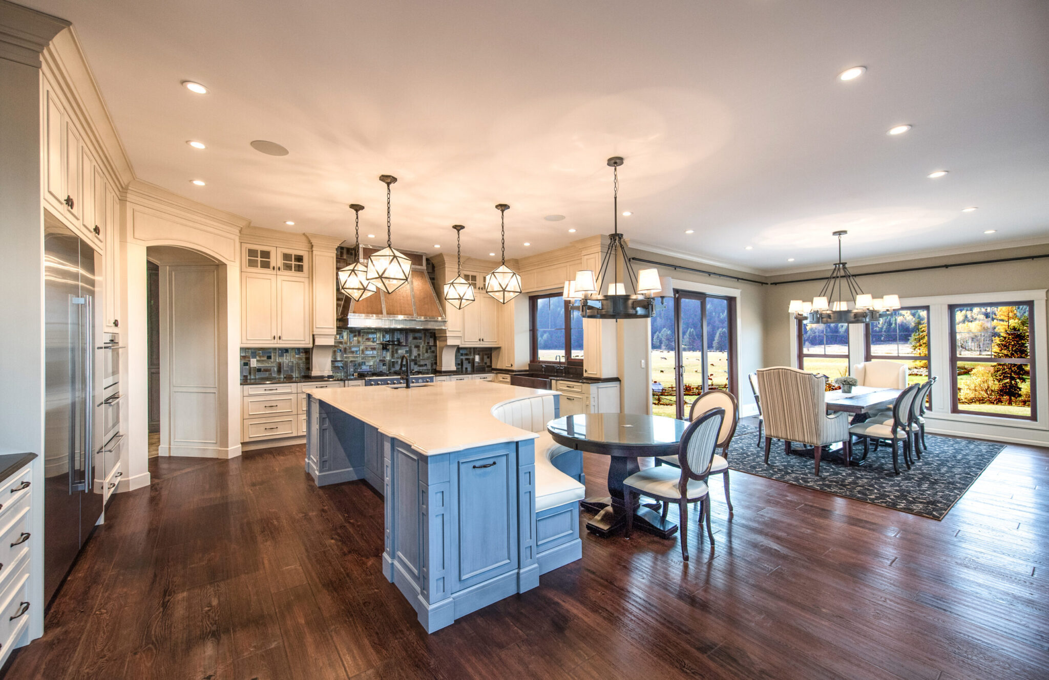 Kitchen with a white island, dark hardwood floors and a dining area beyond