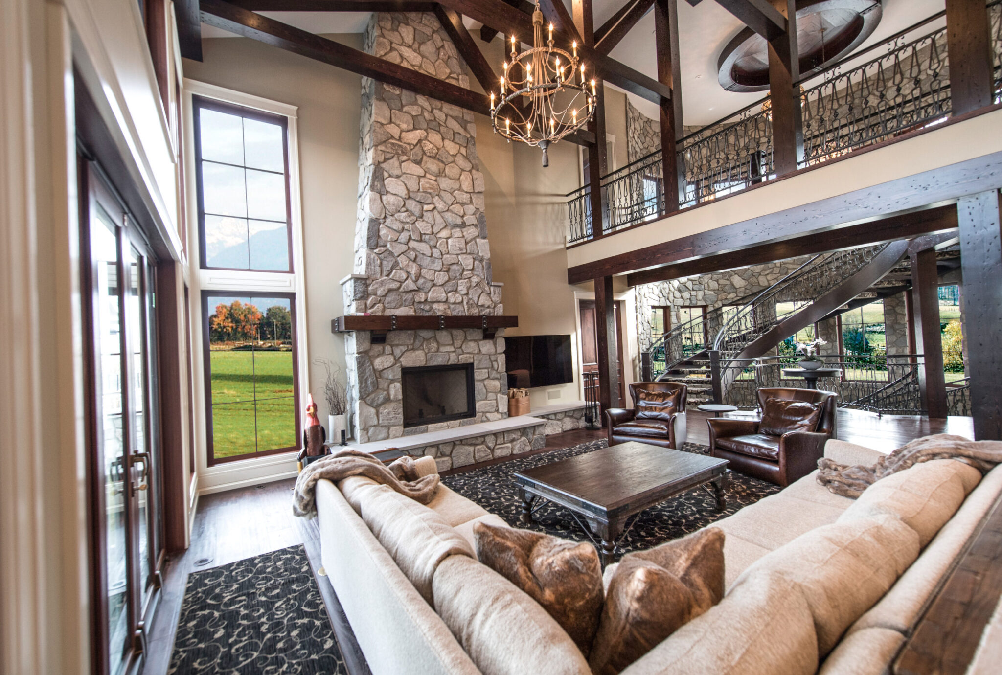 Great room with a stone fireplace, timber beams and a chandelier, open to the dining room