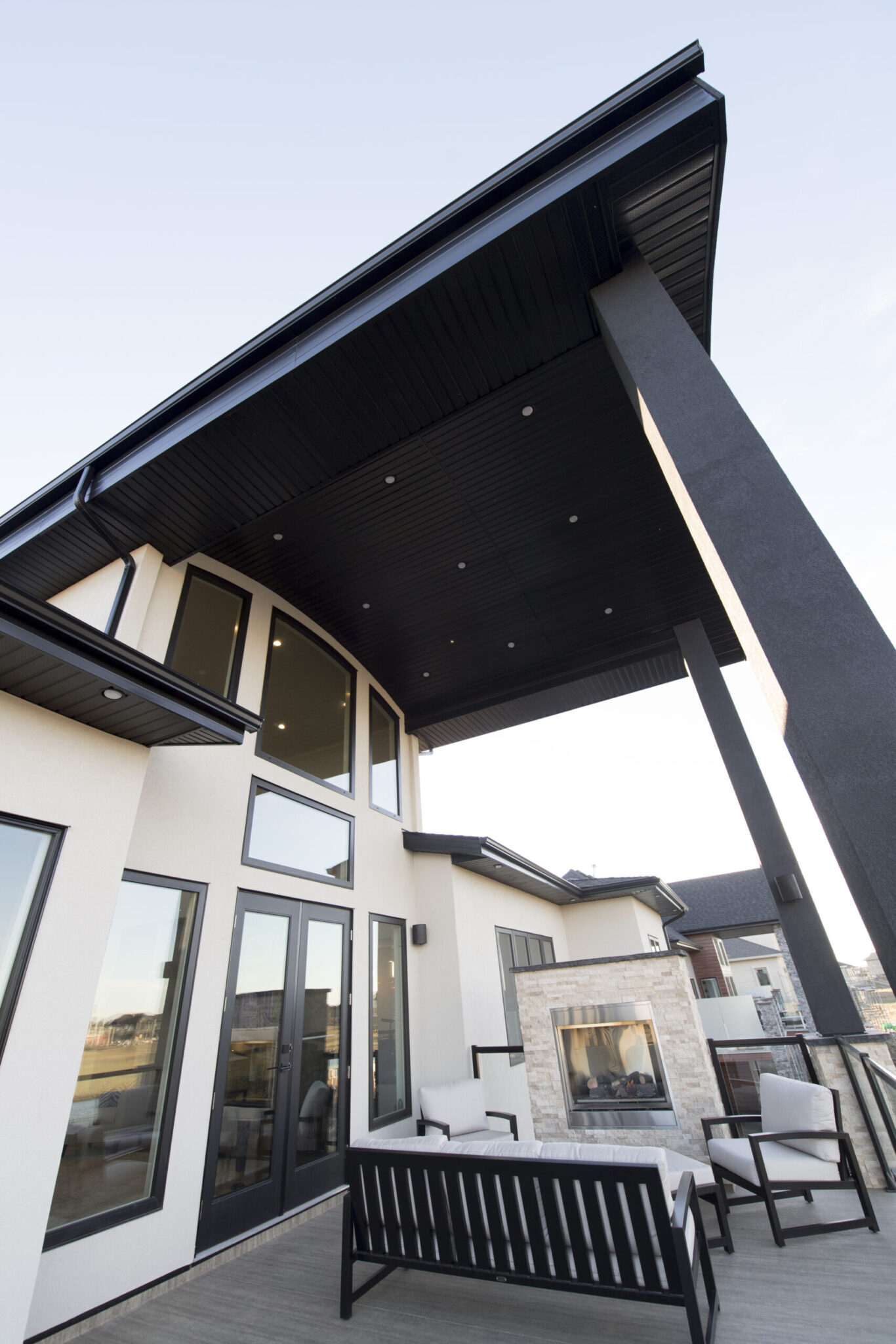 Rear of a contemporary home with a cantilevered roof over a lower-level patio